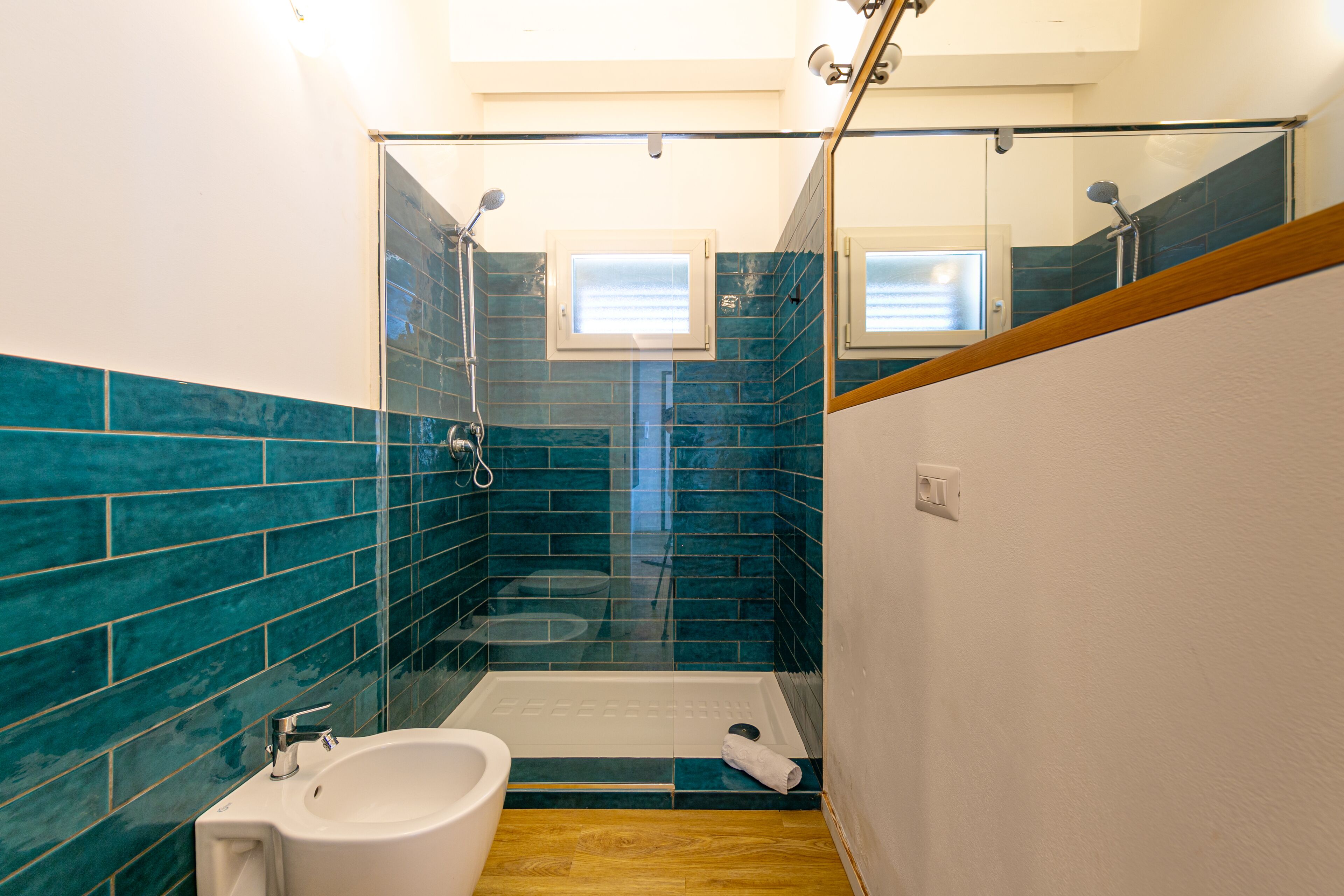 Un baño con cabina de ducha de vidrio, un lavamanos y un inodoro.
