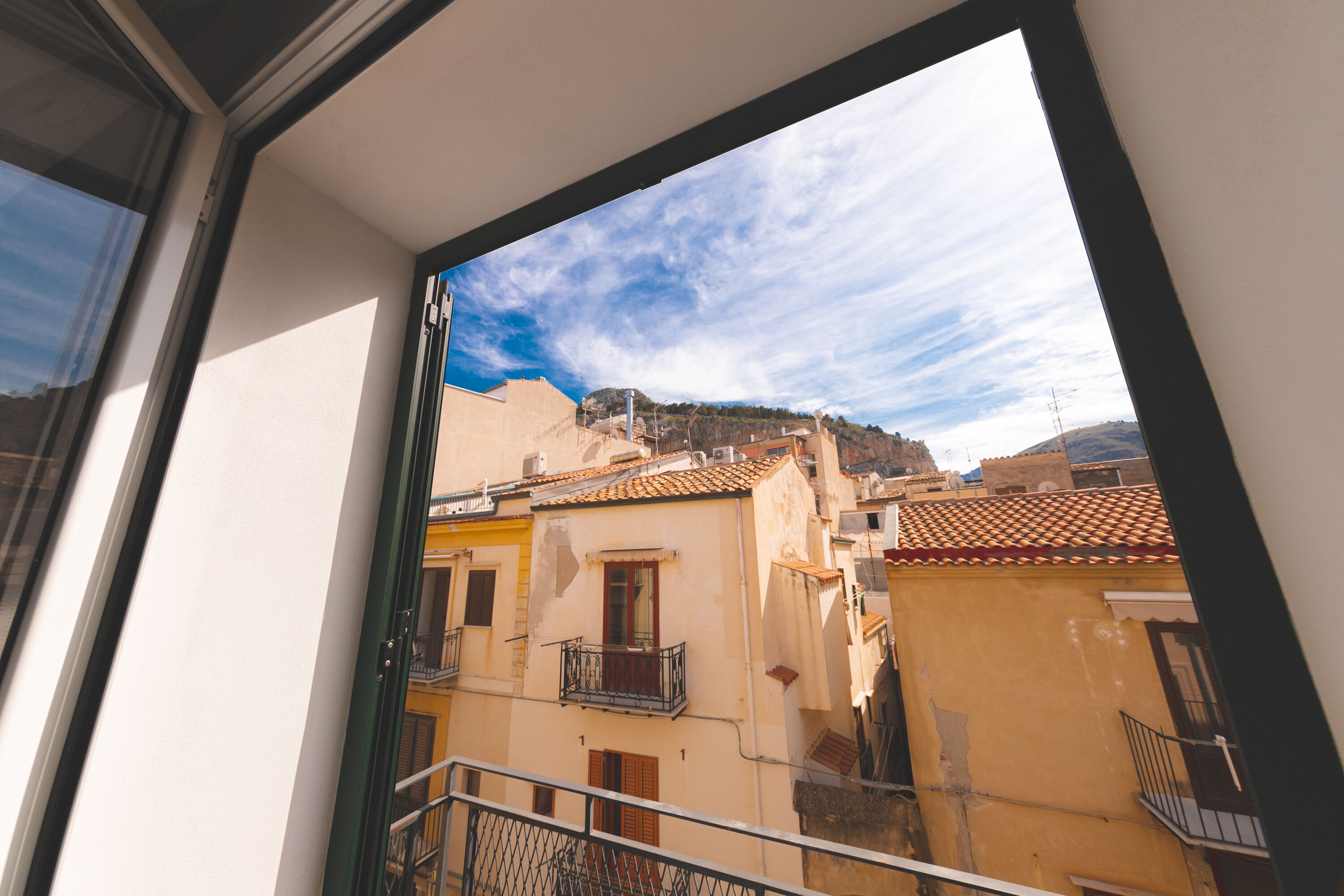 Un balcón con vistas a edificios cercanos y una montaña al fondo.