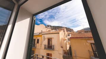 A balcony with a view of neighboring buildings and a mountain in the background.