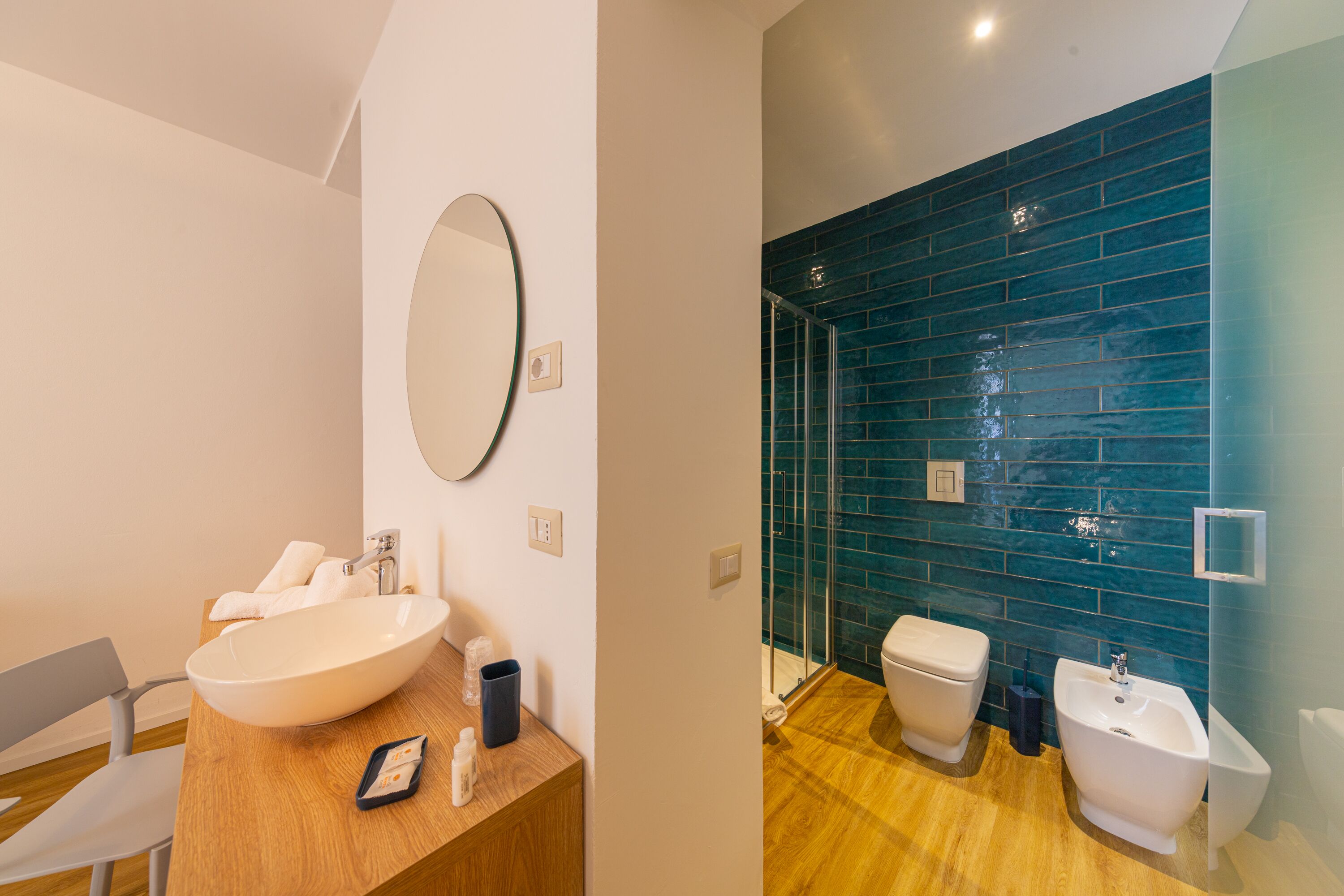 Une salle de bain moderne avec un grand lavabo ovale, un miroir, un meuble-lavabo en bois, une douche avec une porte en verre et des toilettes.