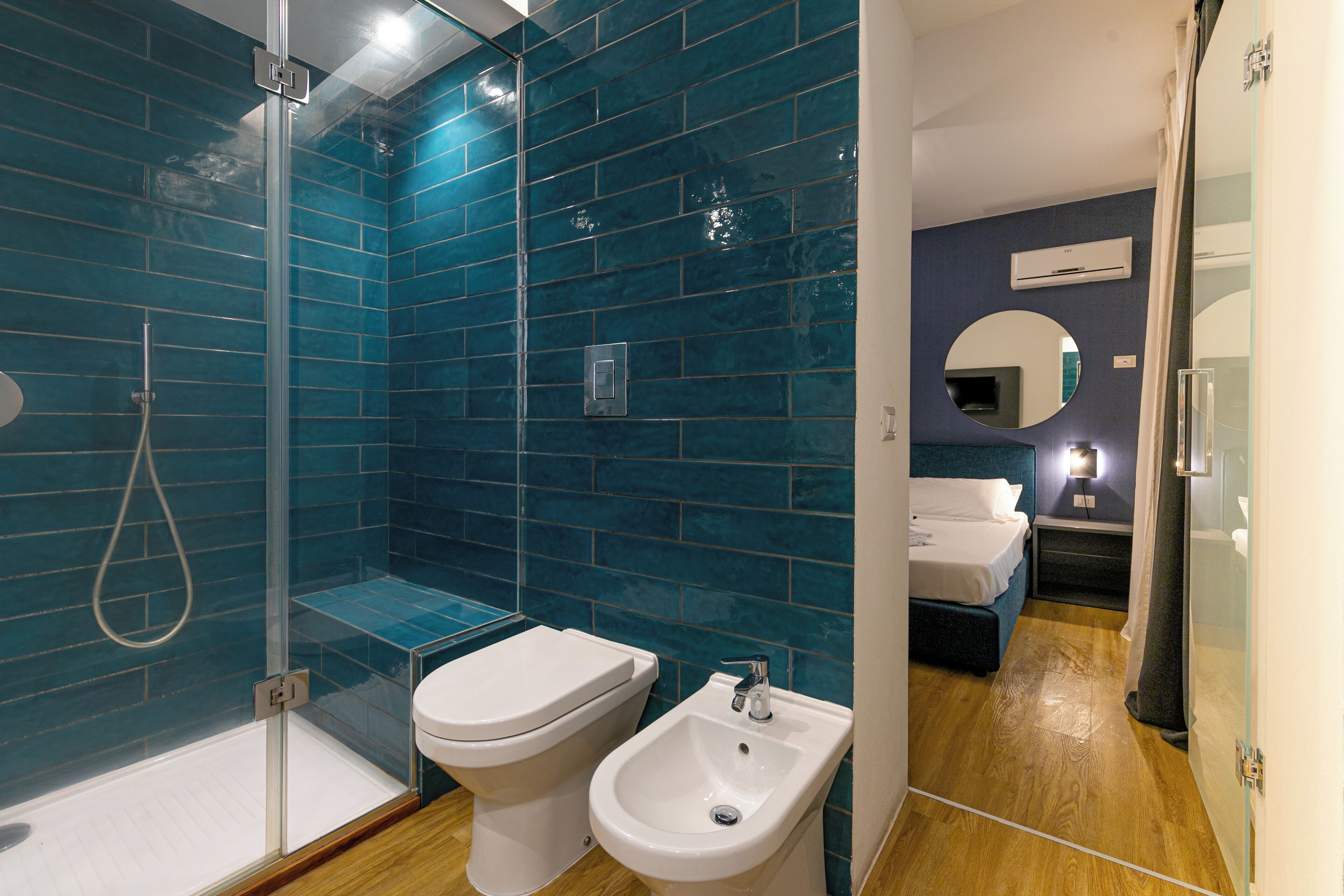 A modern bathroom with a glass shower enclosure, a toilet, and a bidet.