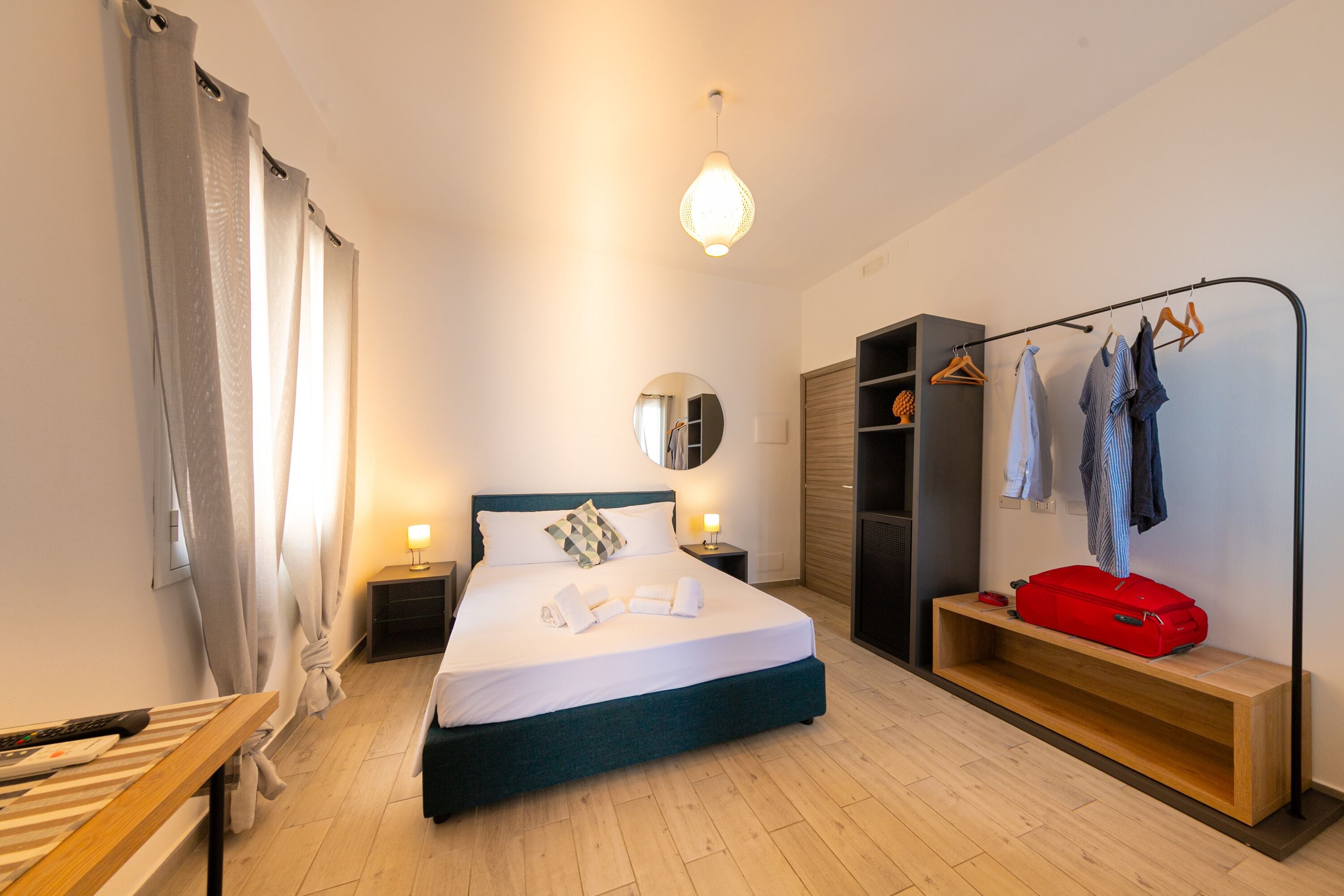 Ein ordentlich eingerichtetes Hotelzimmer mit Bett, Nachttischen, einem Kleiderschrank und einer Bank.