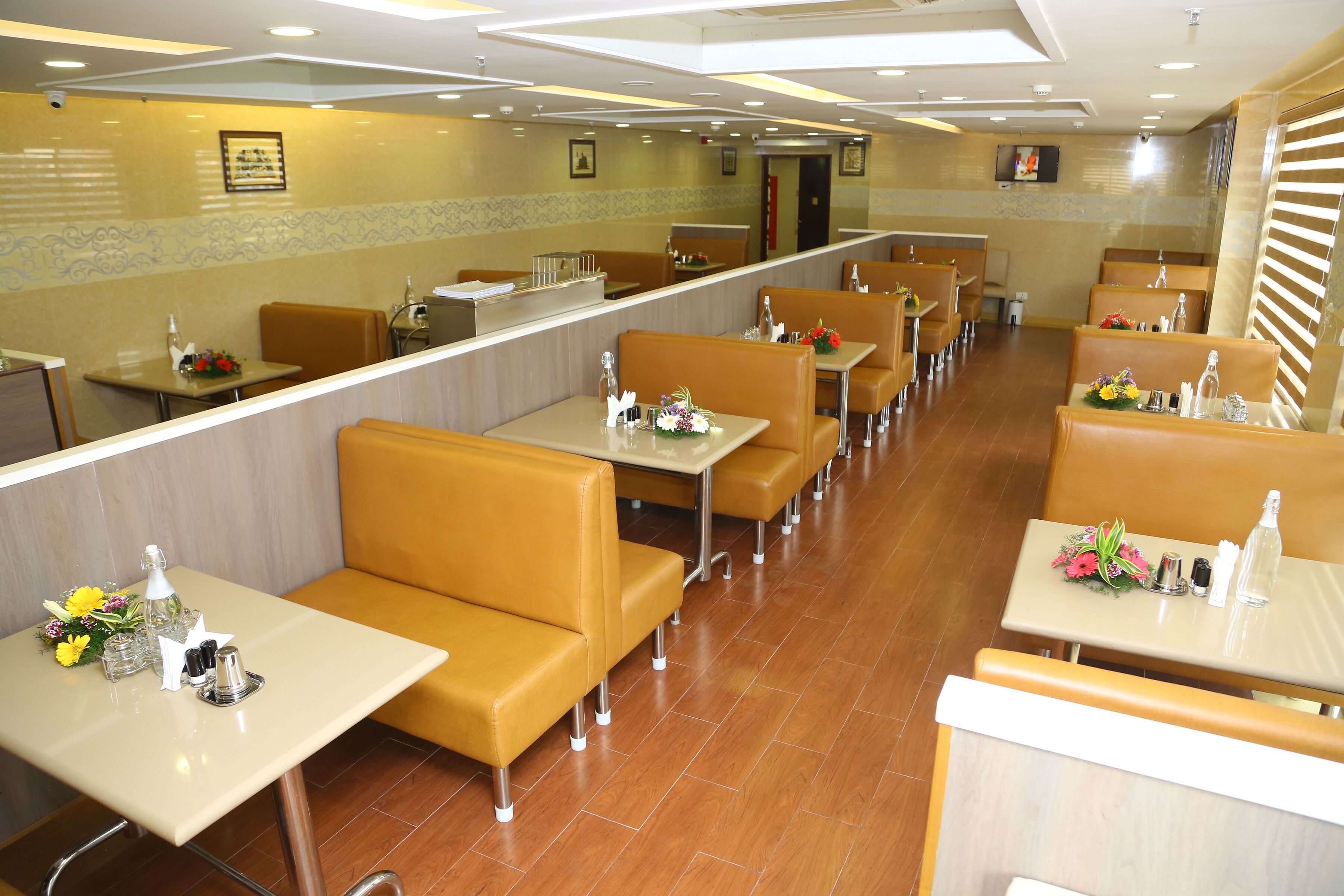 A restaurant with booths and tables, each with a flower arrangement and condiments.
