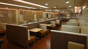 A restaurant with booth seating, wooden partitions, and recessed ceiling lighting. - Raaj Bhaavan Clarks Inn Chennai (Chennai)