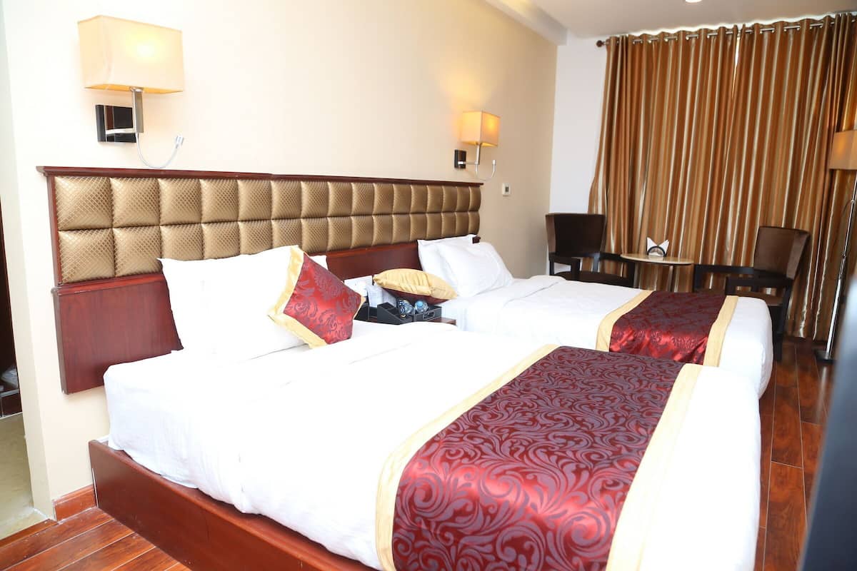 Una habitación de hotel con dos camas, cabeceros de madera, una mesita y una silla.