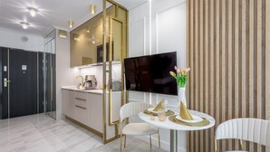 A modern kitchen with a large TV, white chairs, and a dining table with a vase of flowers. - Vacation apartment by the sea, vacation on the island of Usedom, Apartment LIVIDUS 135 (Swinoujscie)
