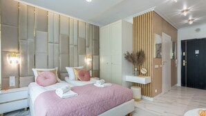 A modern bedroom with a large bed, bedside lamps, a vanity, and a dark door. - Vacation apartment by the sea, vacation on the island of Usedom, Apartment LIVIDUS 135 (Swinoujscie)