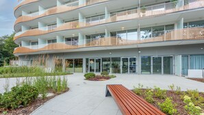 A modern multi-story building with balconies, a central courtyard with a bench, and a glass entrance. - Vacation apartment by the sea, vacation on the island of Usedom, Apartment LIVIDUS 135 (Swinoujscie)