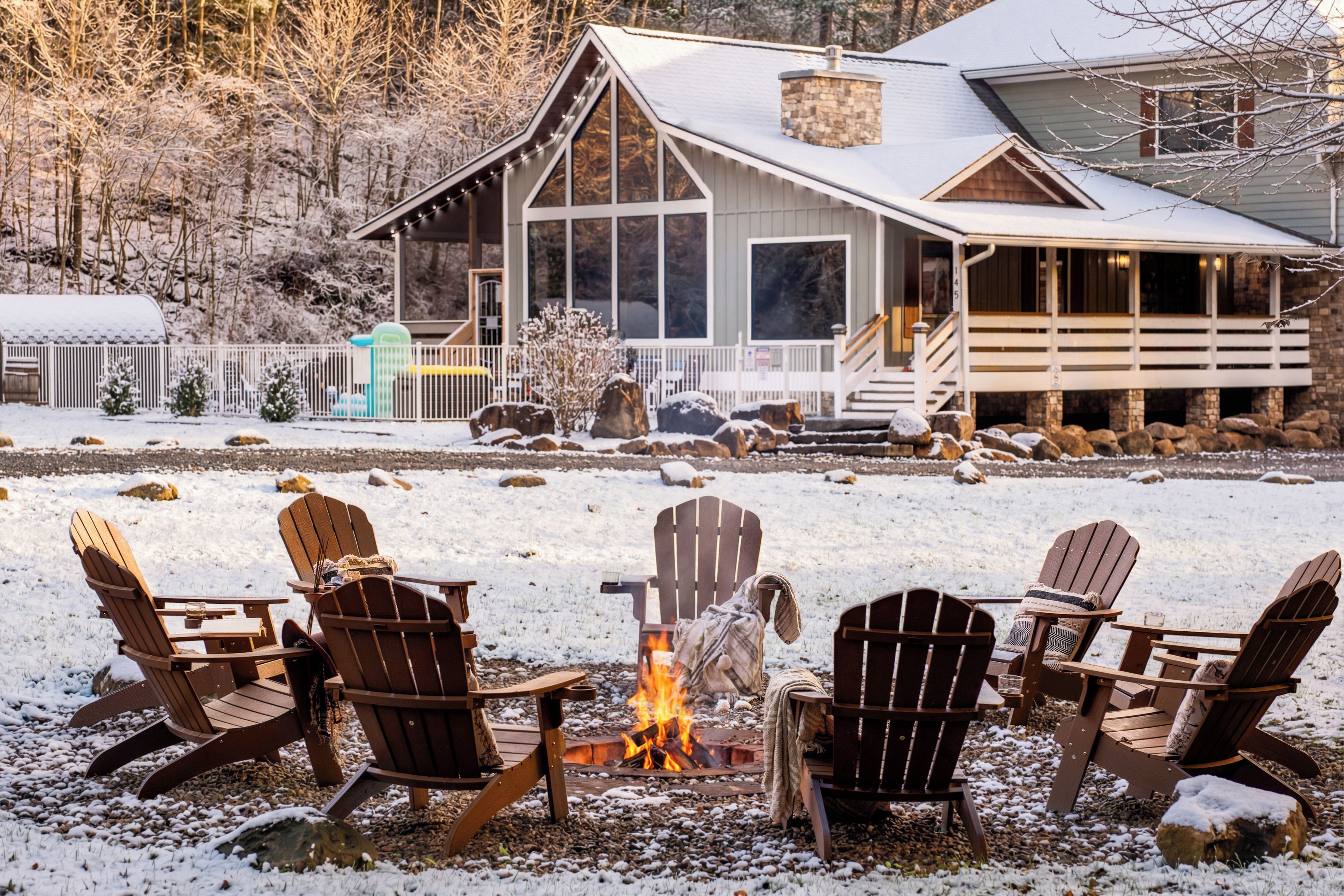 A lodge with a fire pit surrounded by Adirondack chairs.