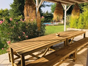 A wooden picnic table with benches, surrounded by lush greenery and flowering plants.