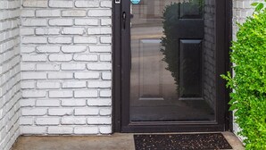 A door with a "Welcome to Our Home" sign, a black door frame, and a white brick wall. - Beautiful home w/easy access to anywhere in Tulsa! (Tulsa)