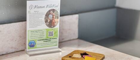 A sign for Missouri Milk Maid soap with a wooden cutting board with cheese and meat.