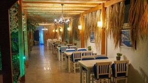Un restaurante con mesas y sillas de madera, piso de baldosas y techo de paja.