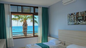 Habitación de hotel con dos camas, vista al mar y un cuadro en la pared.