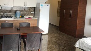 Una cocina compacta con zona de comedor, un refrigerador y un armario de madera.