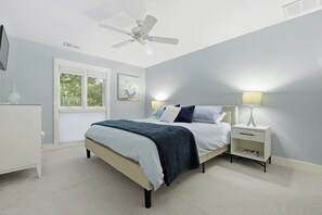 Ein Schlafzimmer mit Bett, Nachttischlampen, Deckenventilator, Fenster und einem Nachttisch.