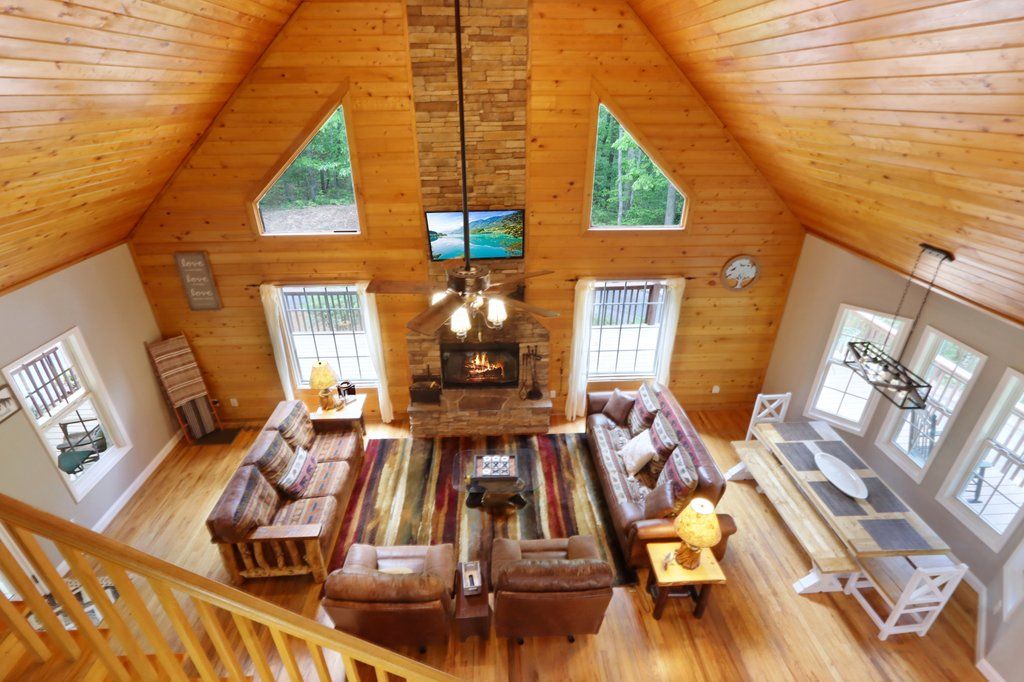 Un loft espacioso con techos altos, una chimenea y un amplio ventanal con vistas a un bosque.