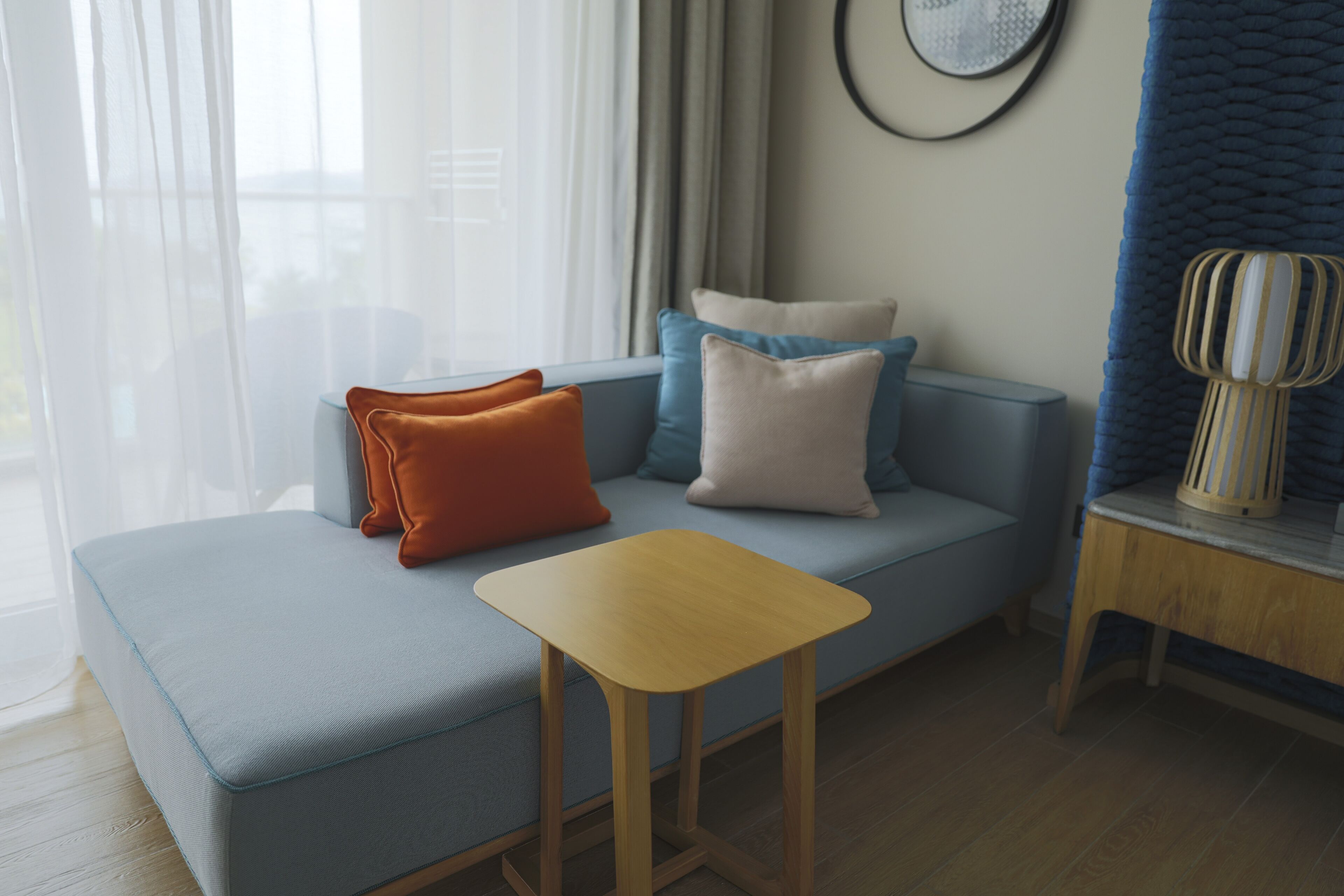 A modern living room with a light blue sofa, a wooden coffee table, and a blue accent wall.