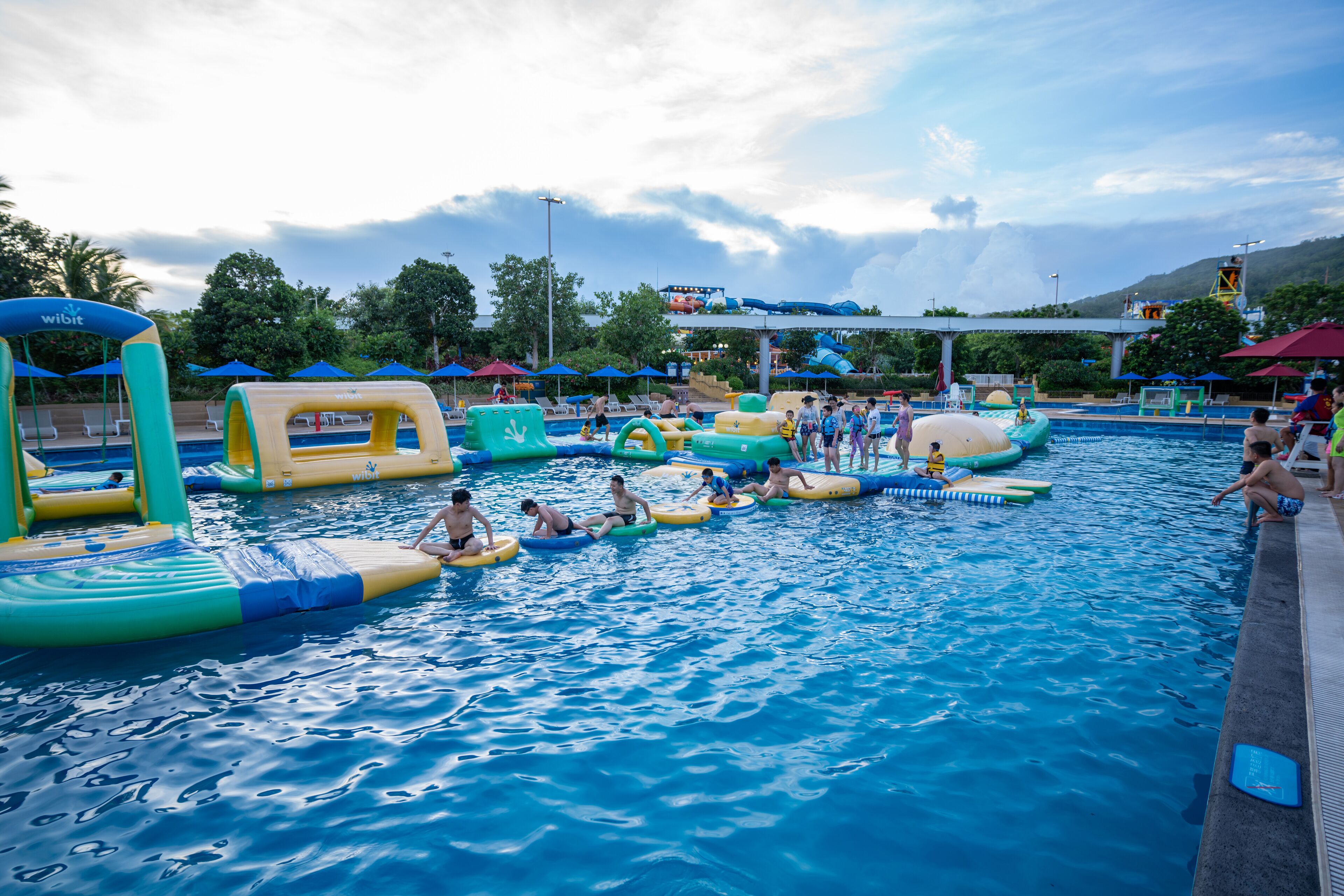 A swimming pool with inflatable water toys and umbrellas.