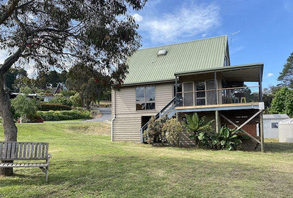 A two-story house with a green roof, a covered porch, and a staircase leading to the upper floor. - Lake & Mountain views with deck and games room for all to enjoy (linen provided) (Goughs Bay)