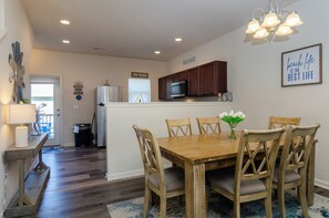 A dining area with a wooden table and chairs, a kitchen with a microwave, and a sign that reads 'NO WAKE'.