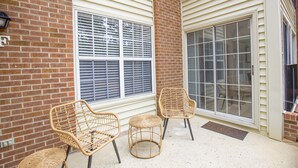 A covered patio area with wicker furniture, a brick wall, and large windows. - 19 F Pinehurst Manor: 1  BR, 1  BA Condominium in Pinehurst, Sleeps 3 (Pinehurst)