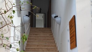 Una escalera conduce a un piso superior, bordeada por paredes blancas y un pasamanos de madera.