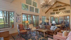 A spacious living room with large windows, a chandelier, and a fireplace. - Beautiful custom home in Chinquapin (Glenville)