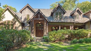 A traditional wooden house with a stone entrance, a well-maintained garden with stone pathways, and a clear blue sky. - Beautiful custom home in Chinquapin (Glenville)