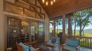 A covered outdoor seating area with wooden furniture and a view of the landscape. - Beautiful custom home in Chinquapin (Glenville)