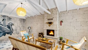 A cozy room with a fireplace, wicker furniture, and a mural of swans. - Rhodium Hotel (Cesme)