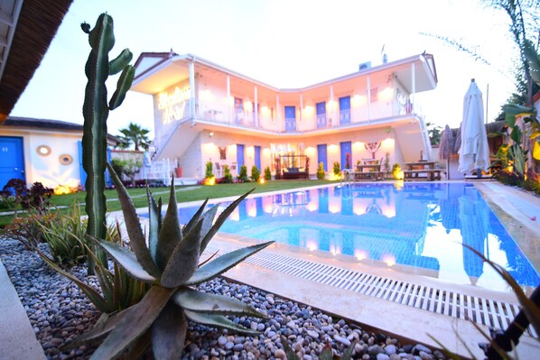 A hotel with a pool, surrounded by plants and a well-maintained lawn. - Rhodium Hotel (Cesme)