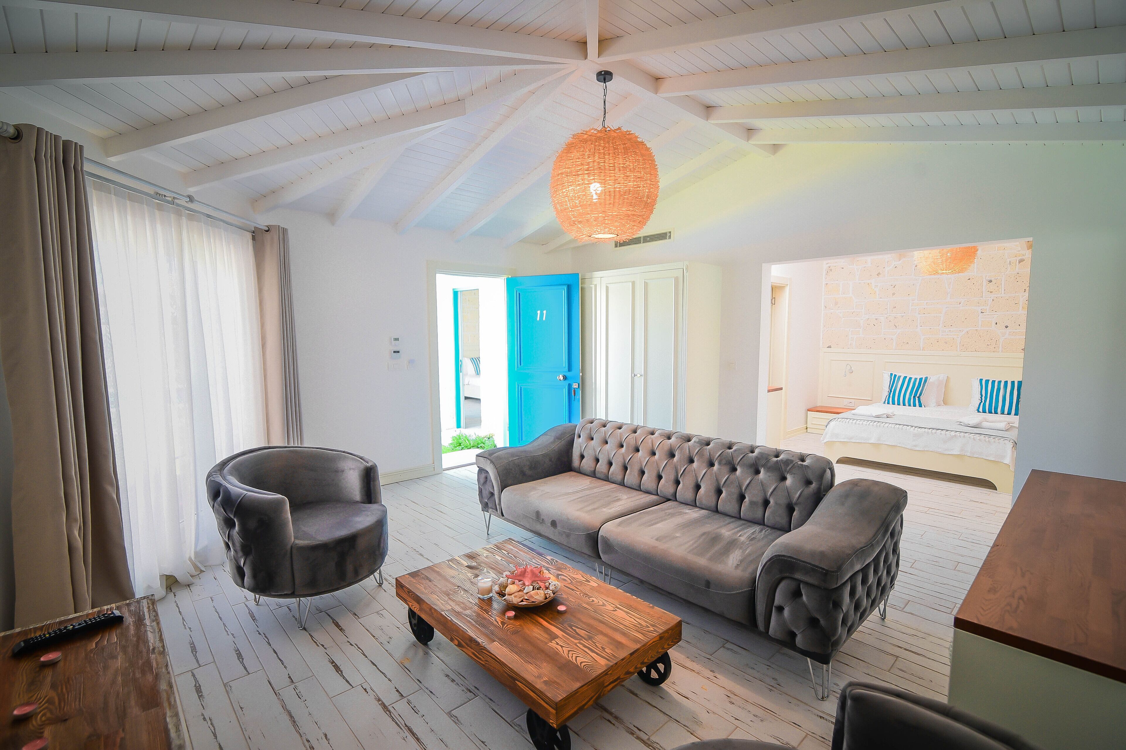 A modern living room with a grey sofa, a round armchair, a wooden coffee table, and a hanging light fixture.