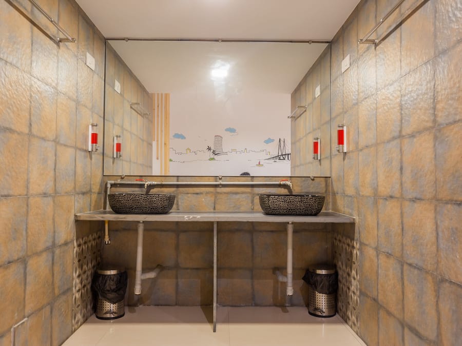 A public restroom with two sinks, tiled walls, and a mural of a cityscape.