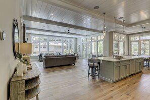 Une cuisine spacieuse dotée d’un grand îlot central, de planchers en bois et bénéficiant d’un éclairage naturel abondant grâce à de grandes fenêtres.
