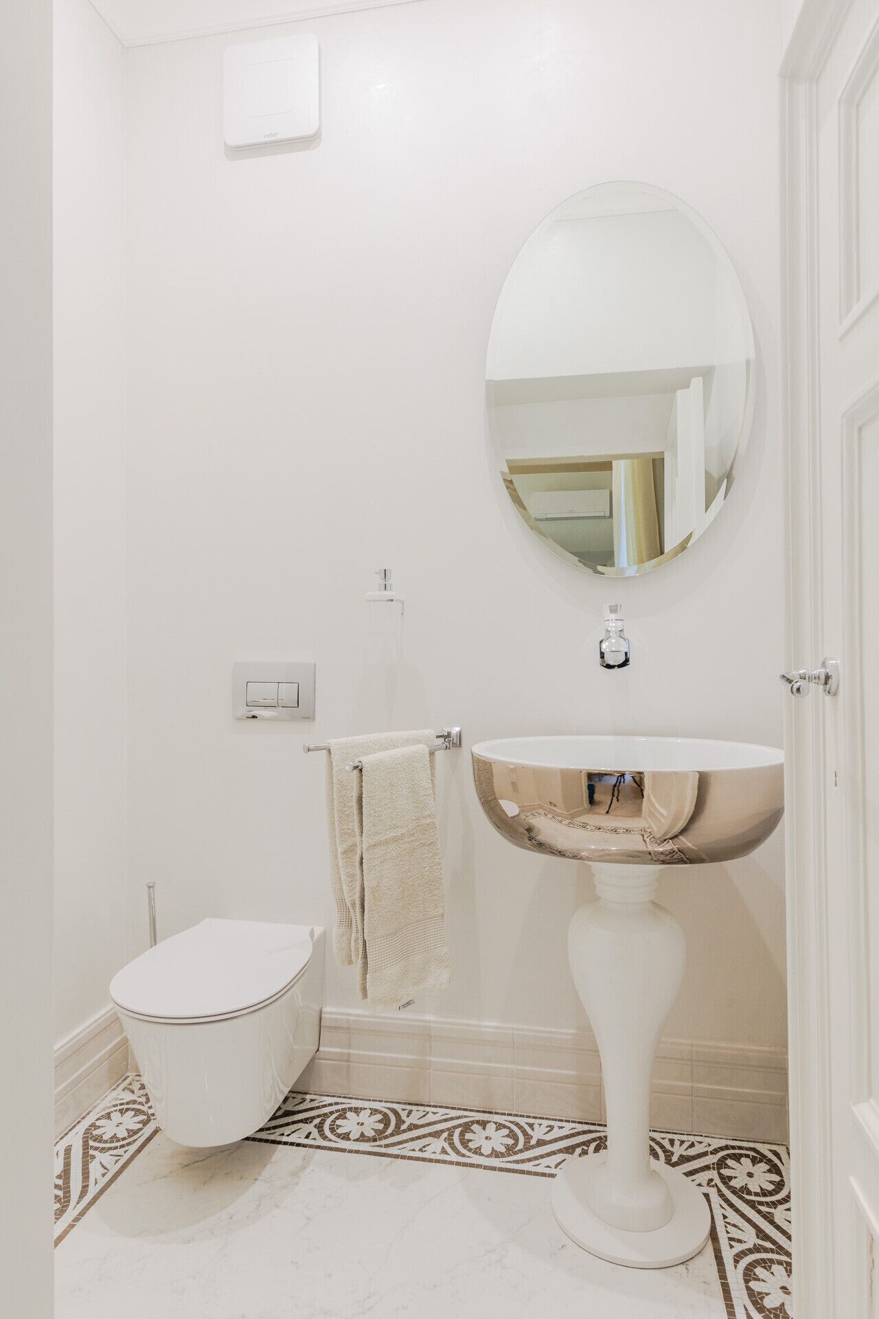 Un baño con inodoro blanco, lavamanos pedestal y espejo sobre el lavamanos.