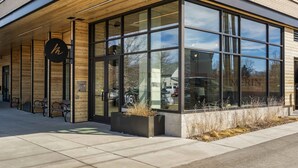 A modern building with large glass windows, a wooden facade, and a bench area outside. - Rustic Overlook- 30 day rental in the new Merin building in downtown Bozeman! (Bozeman)