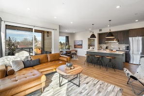 A modern kitchen with a central island, bar stools, and a stainless steel refrigerator. - Rustic Overlook- 30 day rental in the new Merin building in downtown Bozeman! (Bozeman)