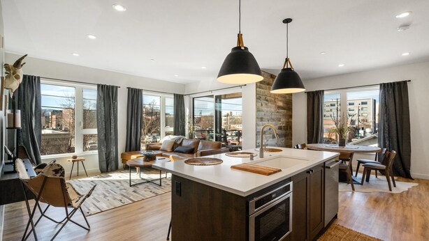A modern kitchen with a central island, large windows, and a view of the city. - Rustic Overlook- 30 day rental in the new Merin building in downtown Bozeman! (Bozeman)