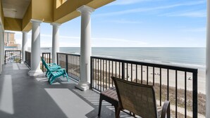 Ein Balkon mit weißen Säulen und Blick auf den Strand.