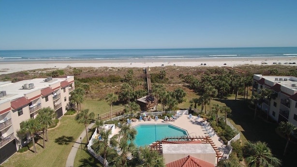 A resort with a swimming pool, beach view, and multiple buildings.