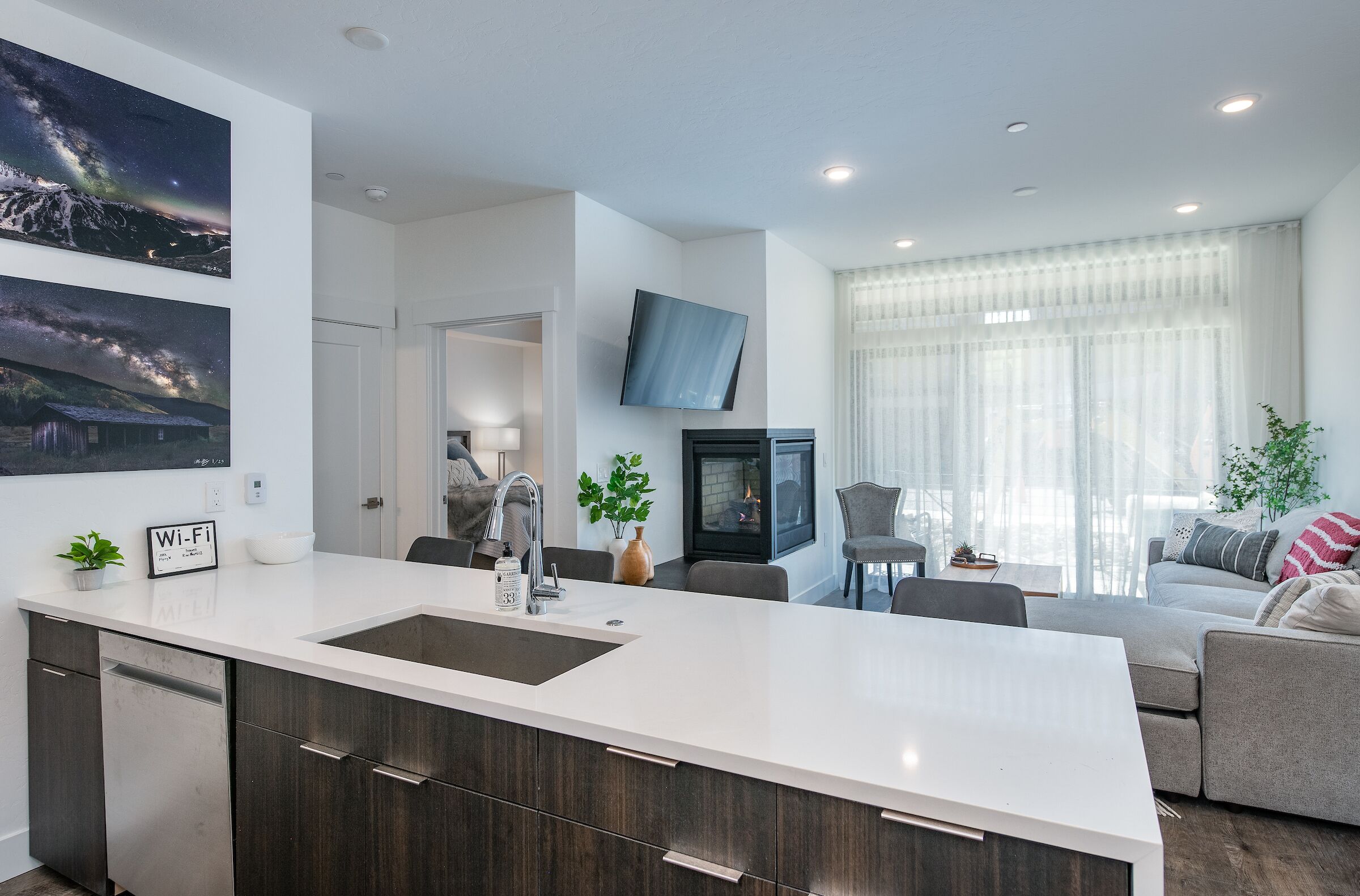 Una cocina moderna con una isla grande, armarios oscuros y encimera blanca.