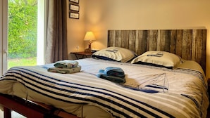Una habitación de hotel con cama, mesita de noche, lámpara y ventana con cortinas.