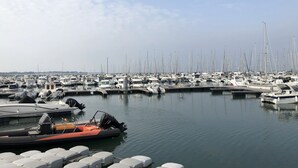 Una marina con numerosos barcos amarrados, un bote inflable pequeño en primer plano y agua tranquila.