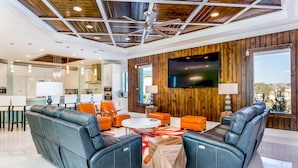 A modern living room with a ceiling fan, leather sofas, a flat-screen TV, and a wooden accent wall. - Last Minute Disney Getaway! Private Pool, Hot Tub & Game Room. Book Now! #6266 (Orlando)