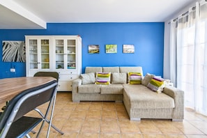 Een woonkamer met een bank, een eettafel en een kast.