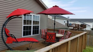 A deck with a curved chair and a table, surrounded by a wooden fence.