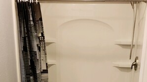 A bathroom with a toilet, a shower, and a sink.