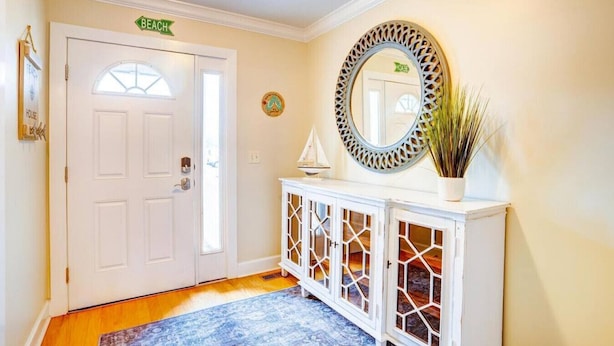 A hallway with a white door, a decorative mirror, a cabinet with glass doors, and a blue patterned rug. - Seniors welcome! Large Townhouse near Boardwalk and Beach!! (Ocean City)