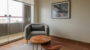 A modern living room with a grey sofa, a wooden coffee table, and a framed picture on the wall.